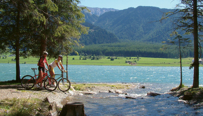 Radfahrer stehen an einem Fluss in den Alpen